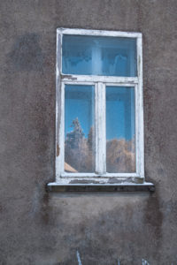 Old windowpane with frosted flowers and reflection of a sunny, wintry landscape in gray facade in Vosges, France Old windowpane with frosted flowers and reflection of a sunny, wintry landscape in gray facade in Vosges, France